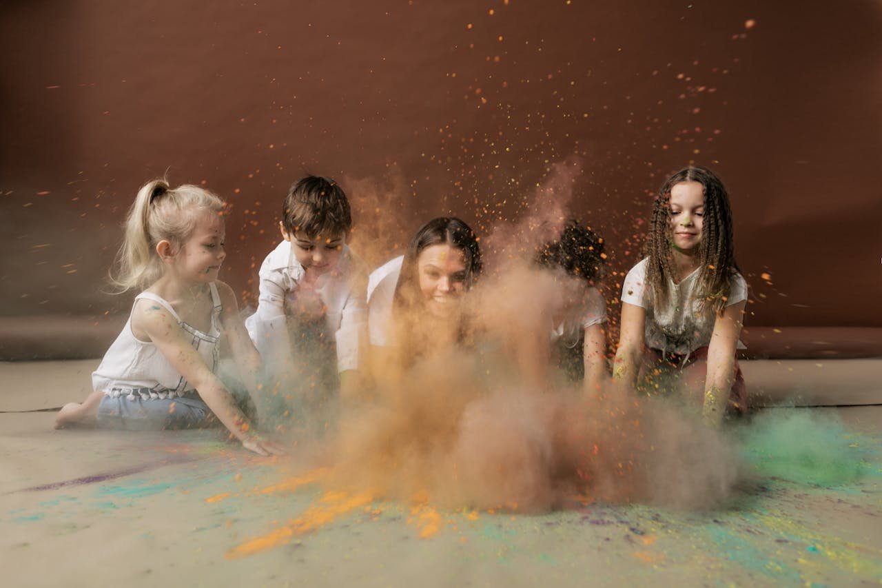 Cheerful children playing with vibrant colored powder, celebrating Holi indoors.